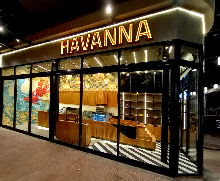 Local Havanna de noche: frente vidriado con cartel luminoso, madera y mural interior